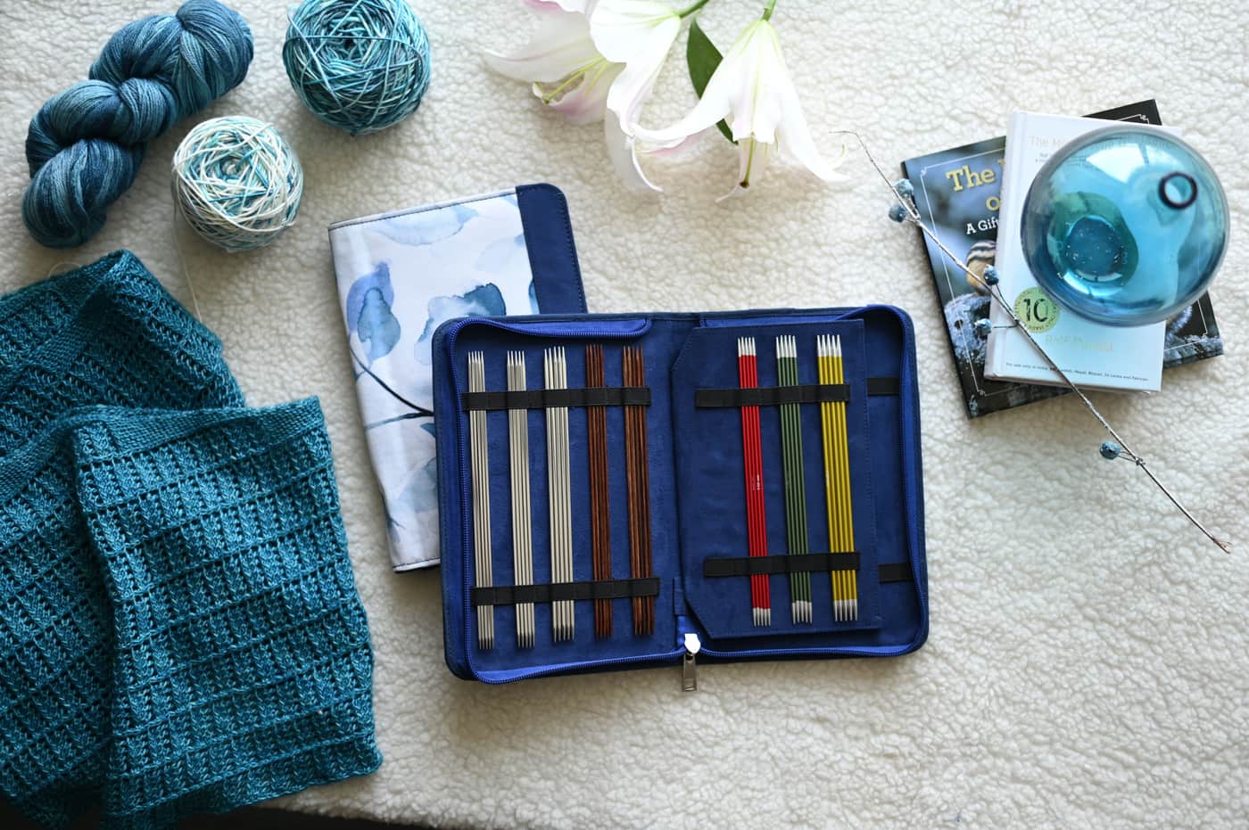 A canvas yarn storage tote with a project and needles beside it