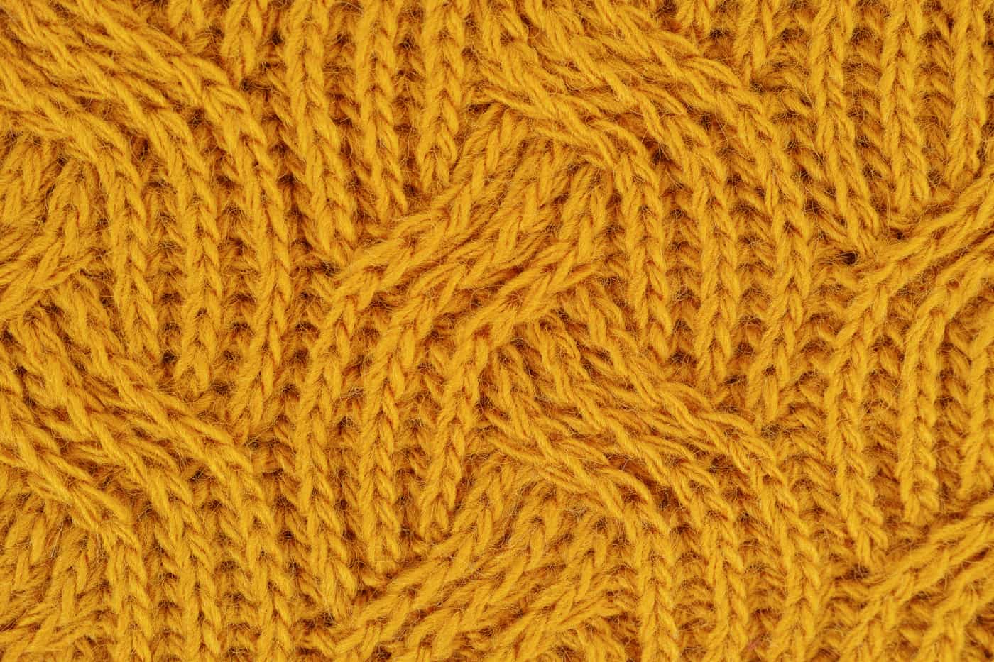 Small cable stitch holders resting on a cabled knitted swatch