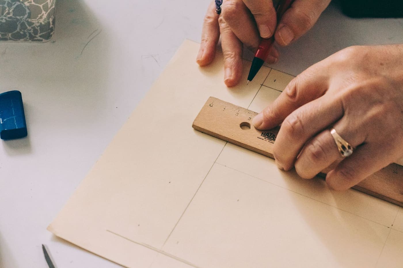 Close-up of hands using a ruler to draw lines on paper