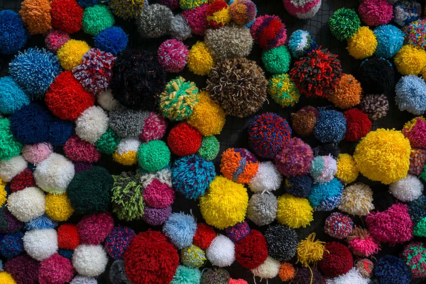A collection of handmade yarn pom-poms in a variety of colors