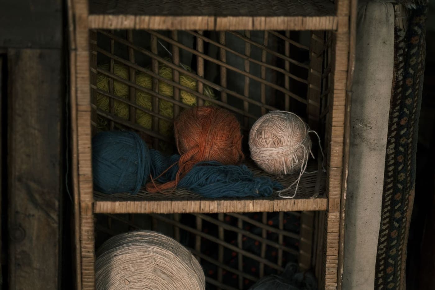 Balls of colorful yarn arranged on a rustic wooden shelf