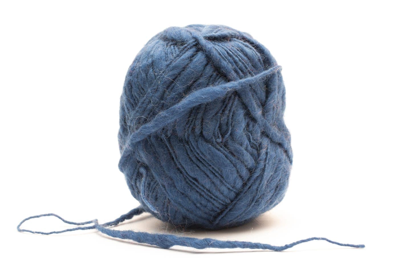 Undyed alpaca fiber next to a skein of fine merino wool on a neutral background