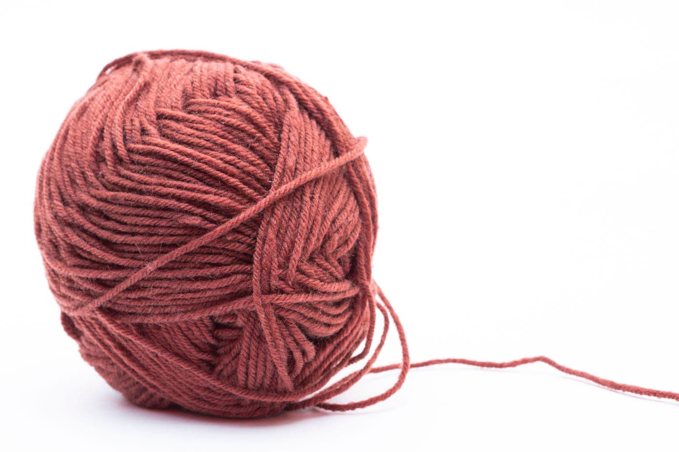 A skein of wool and acrylic blend yarn beside a knitted swatch