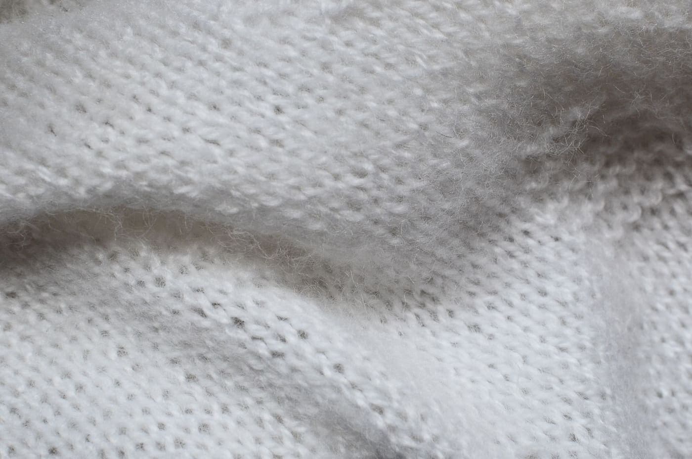 Top view of a textured white knitted woolen textile on a table