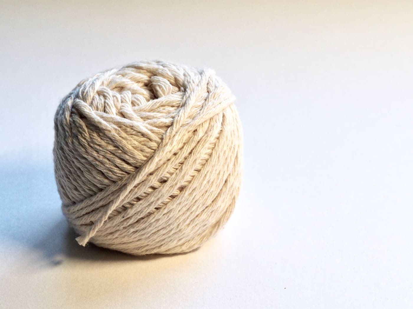 A ball of natural cotton yarn on a white background