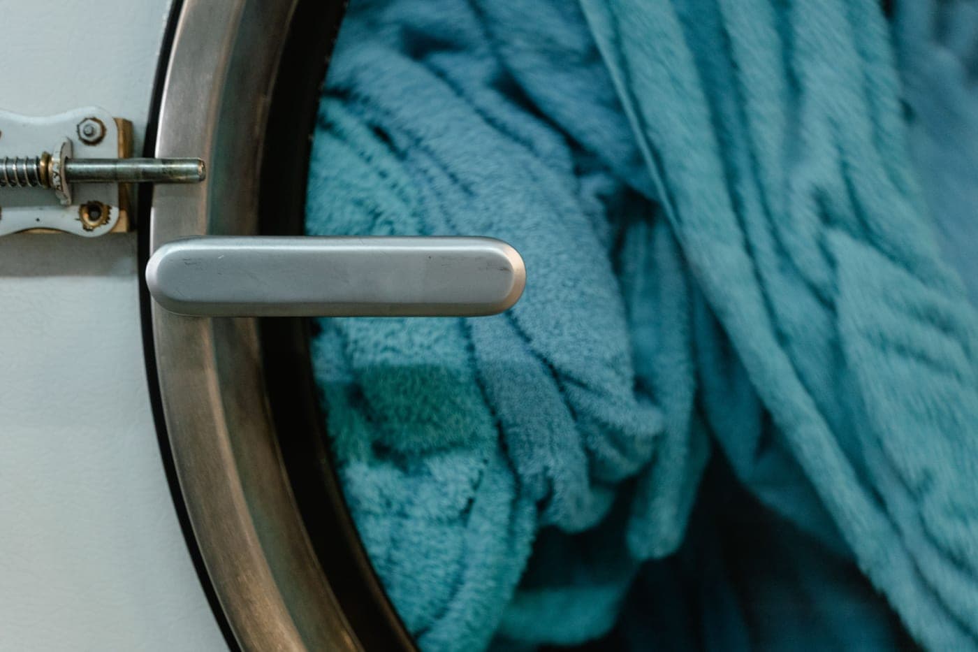A ball of smooth acrylic yarn beside a washing machine drum door