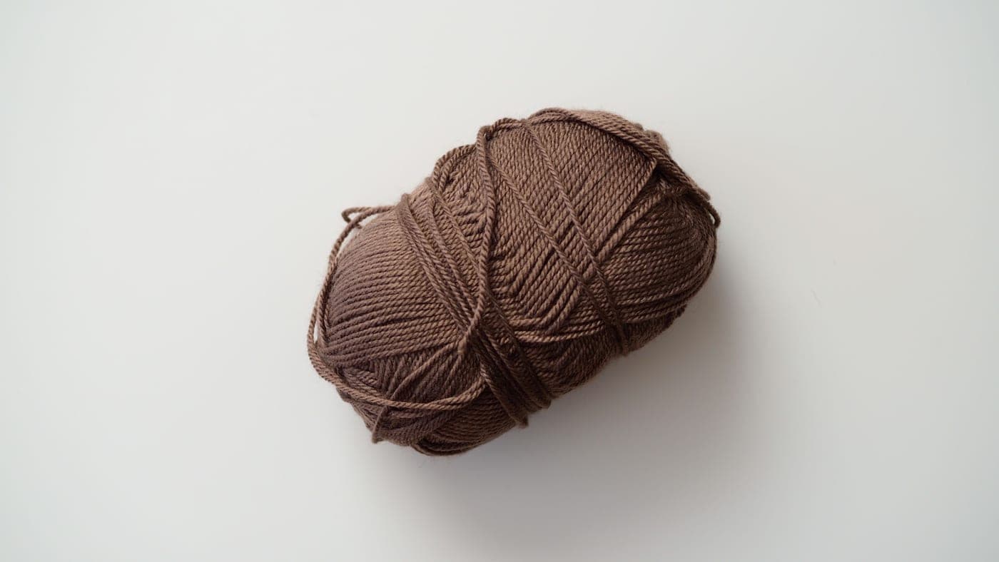 Two skeins of wool yarn side by side, one smooth and one with a matte woolen finish