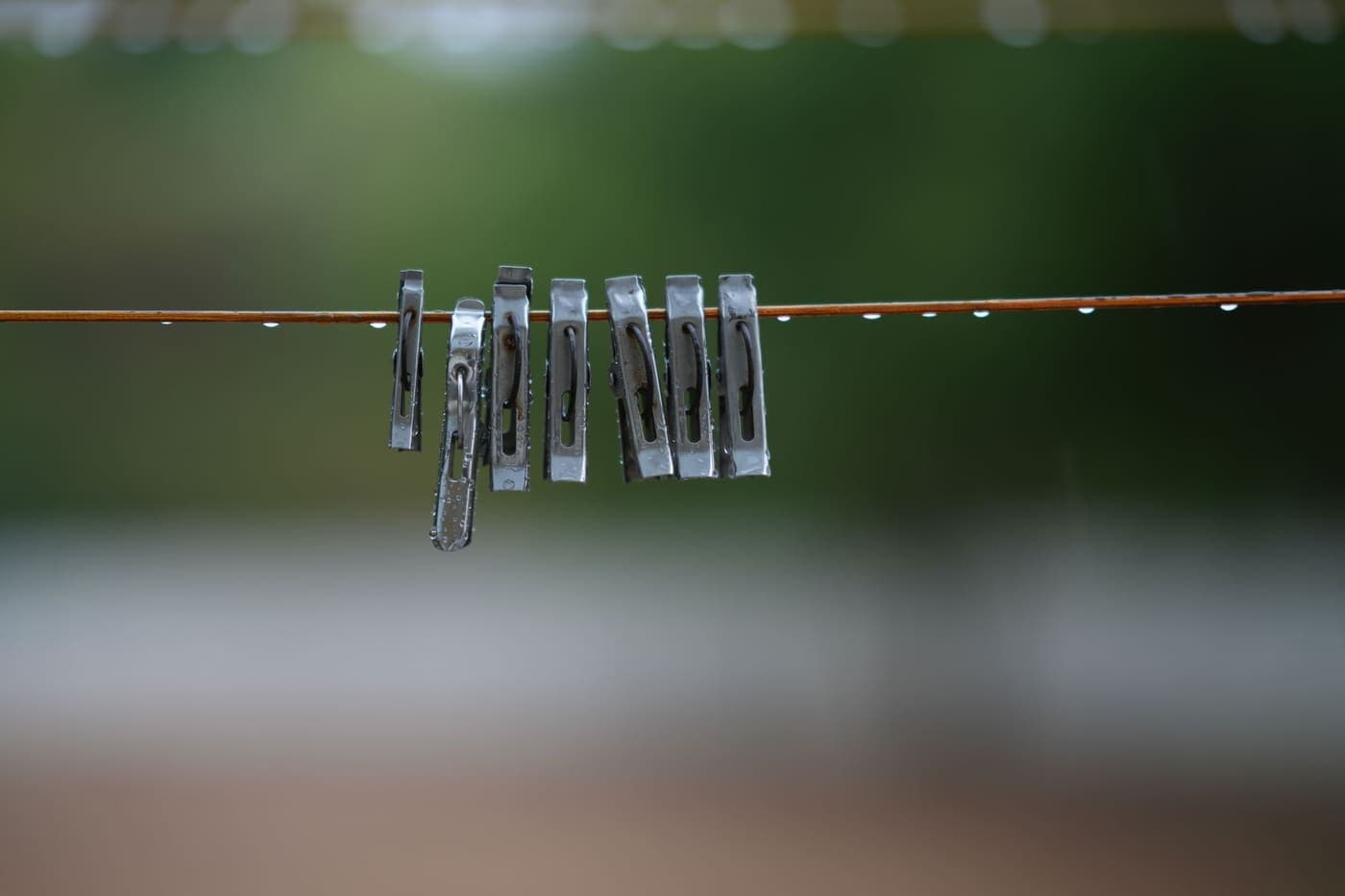 Metal clothespins holding damp fabric on a washing line outdoors