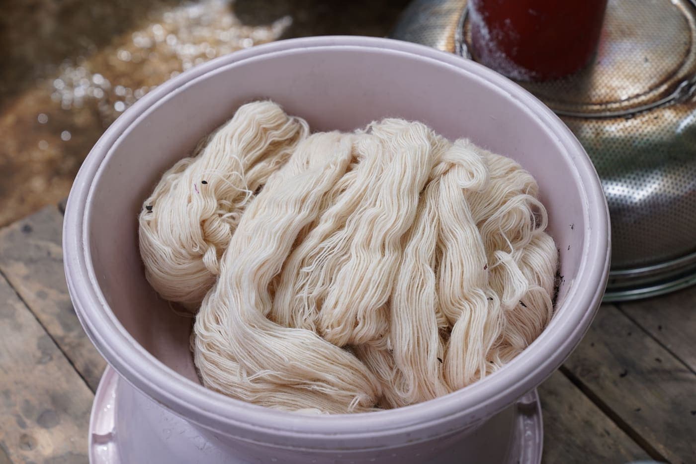 Natural white yarn soaking in a pink basin of water