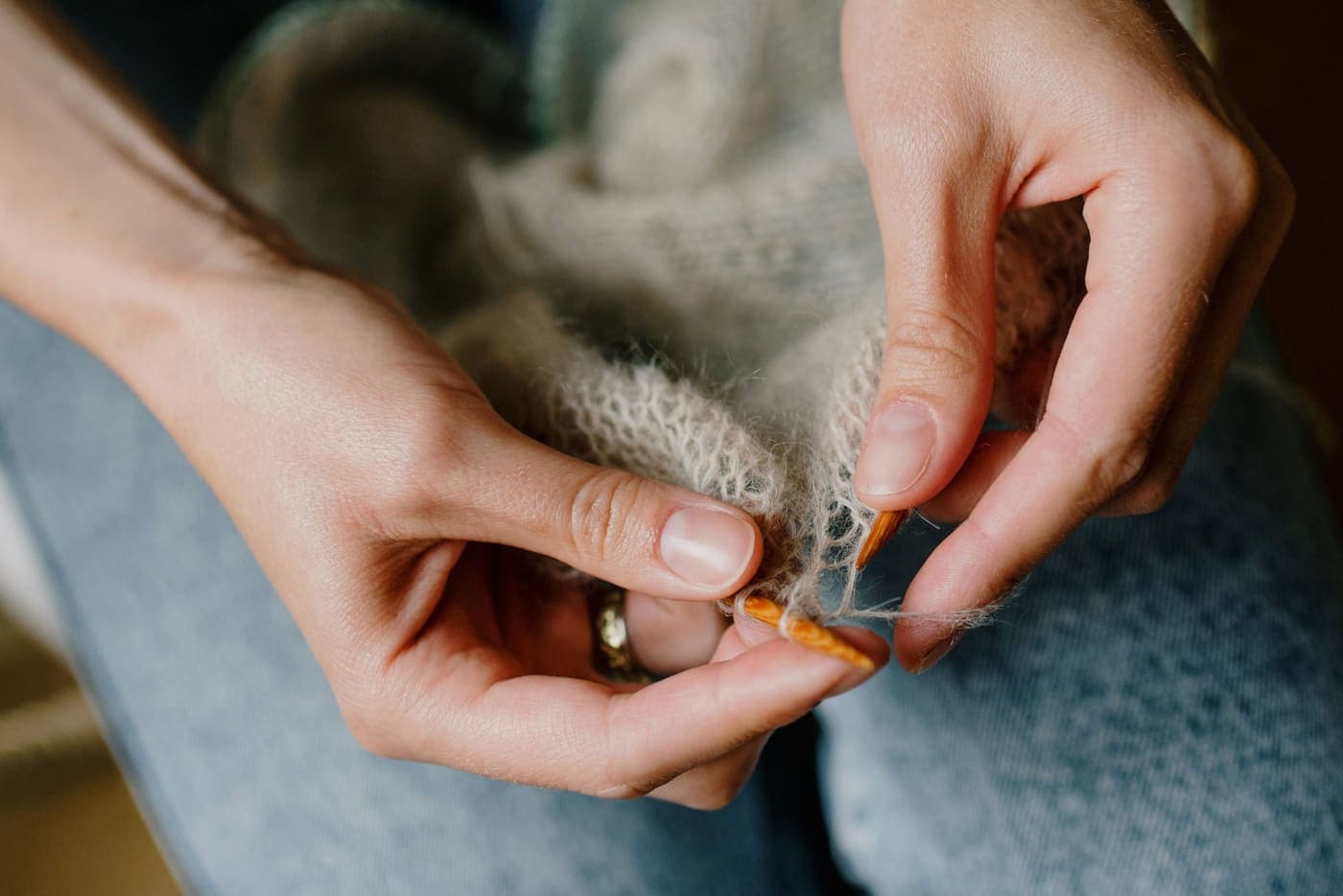 A close view of hands working with soft pale knitted fabric