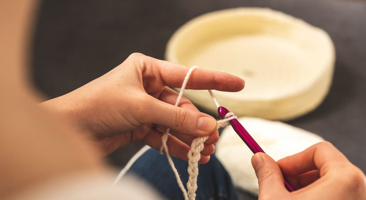 A beginner yarn project in progress with a single hook and one ball of yarn