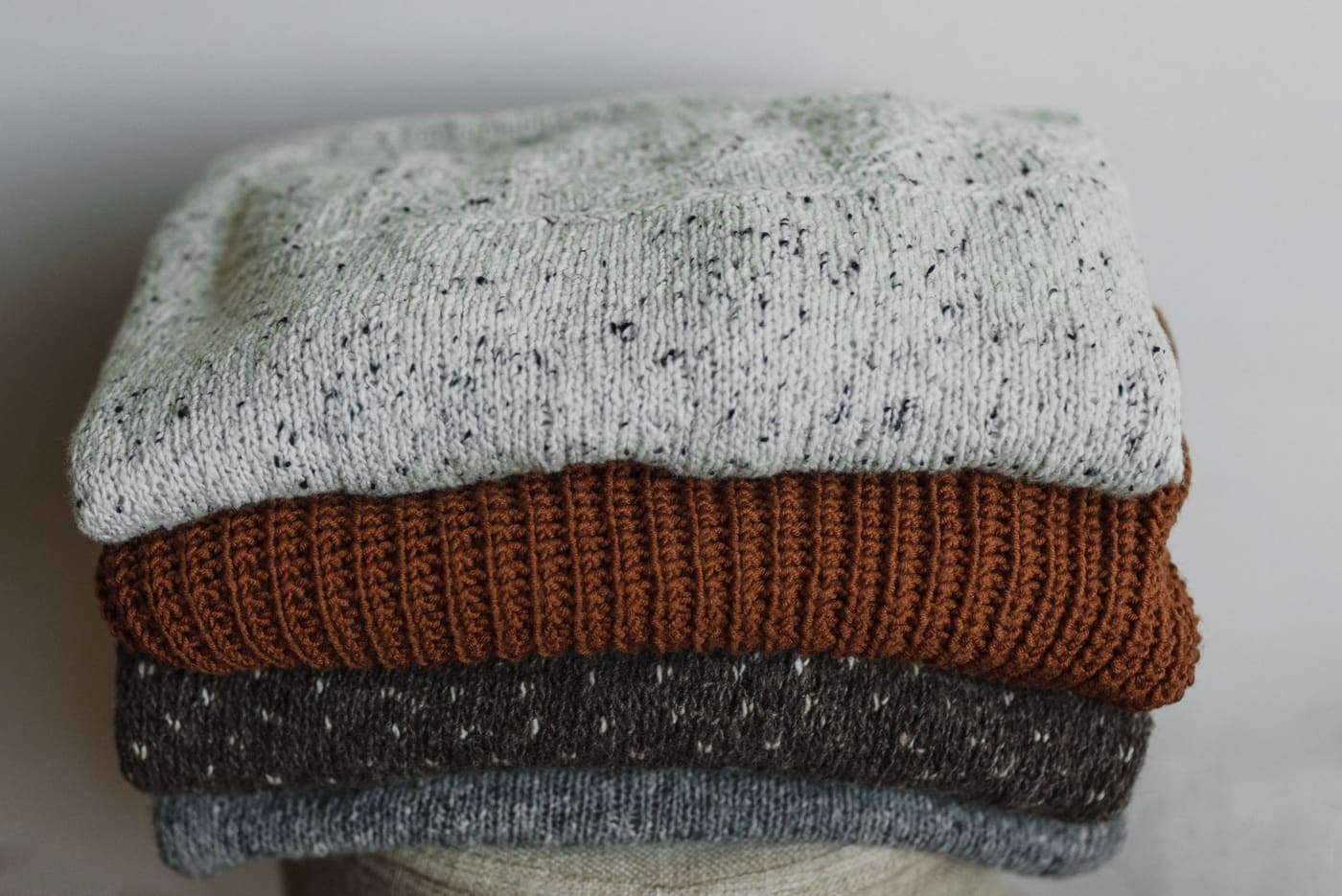 Close-up of folded knitted sweaters in neutral tones