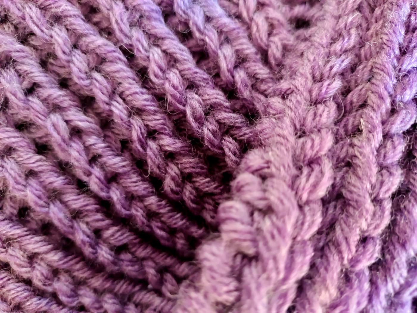 Close-up of purple knitted fabric showing rows of stitches