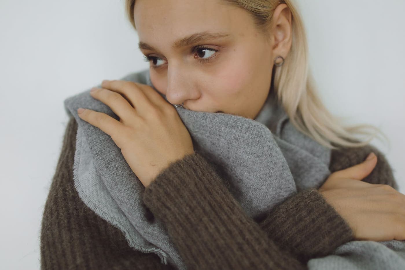 A person wrapped in a soft gray scarf indoors