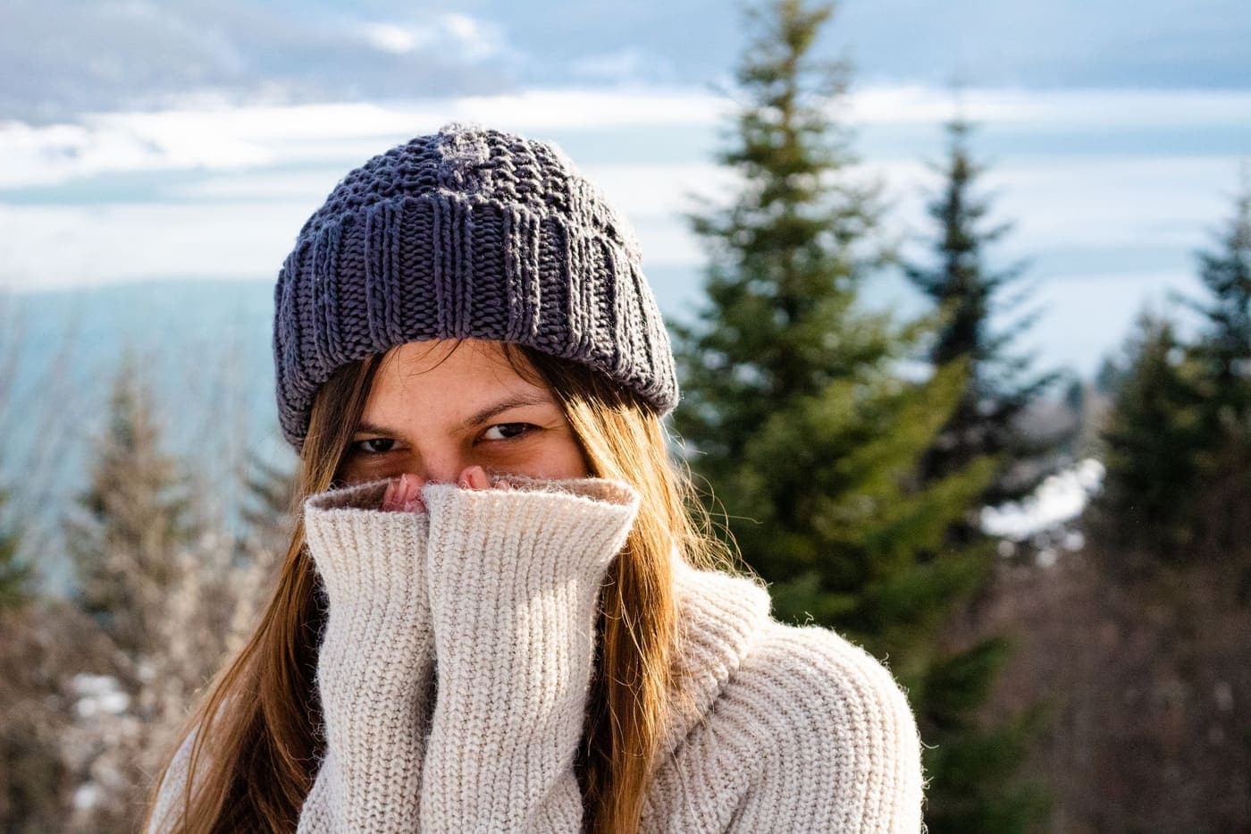 A person in a knitted sweater and beanie outdoors in winter