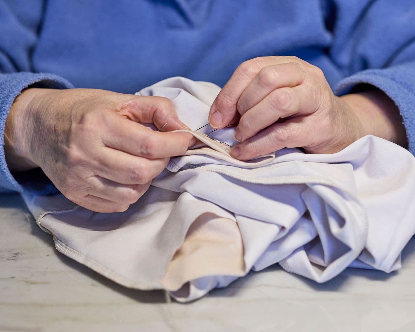 Close-up of hands sewing white fabric