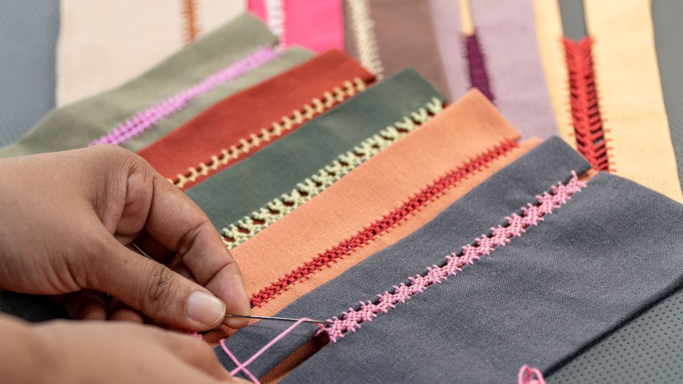 Close-up of hands stitching yarn into colorful fabric