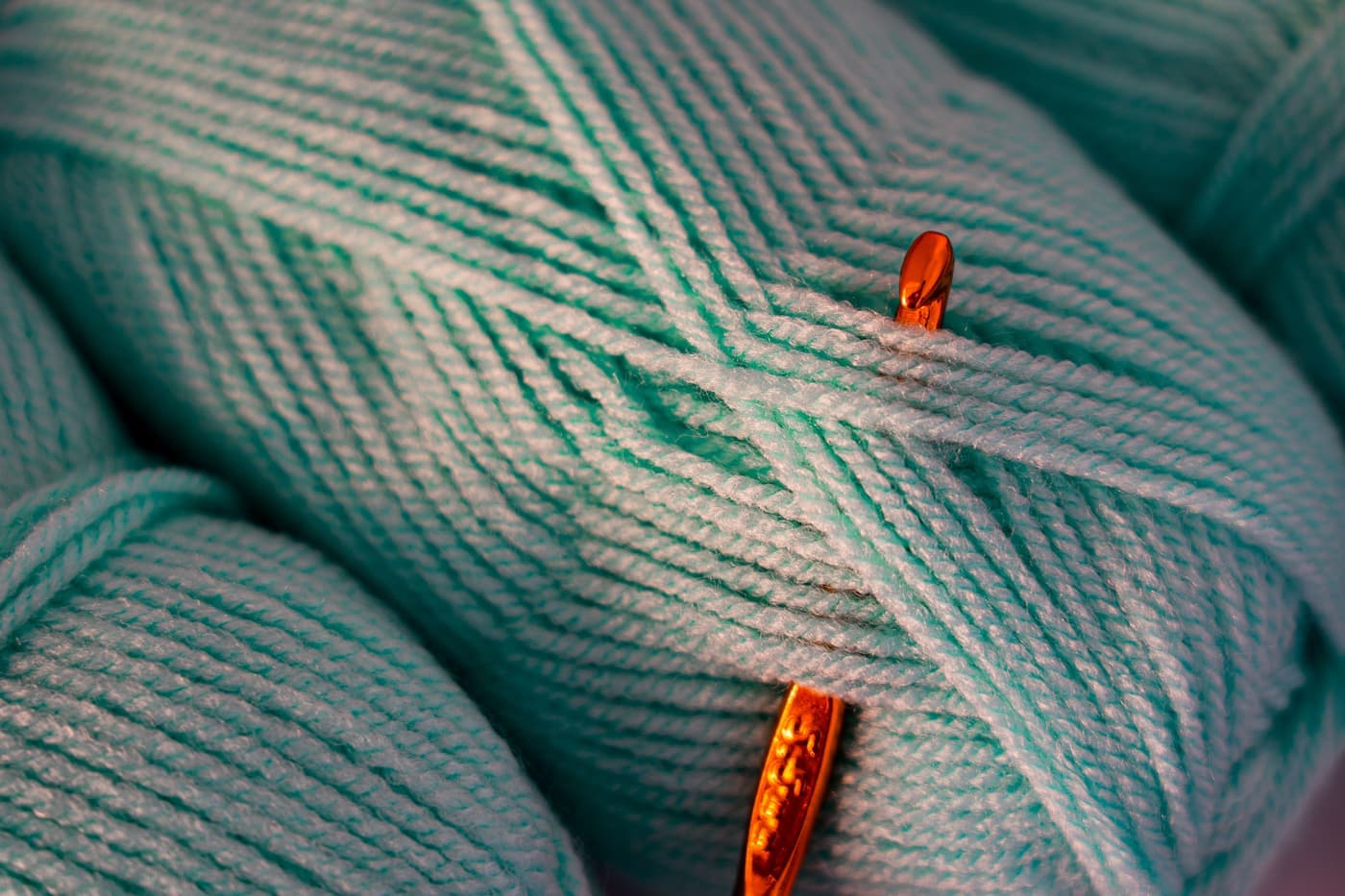 A crochet hook working into smooth worsted weight acrylic yarn