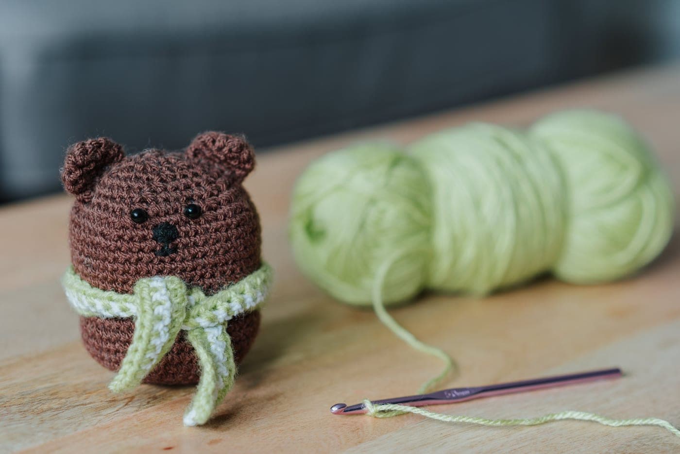A single crochet hook resting on a beginner swatch of worsted weight yarn
