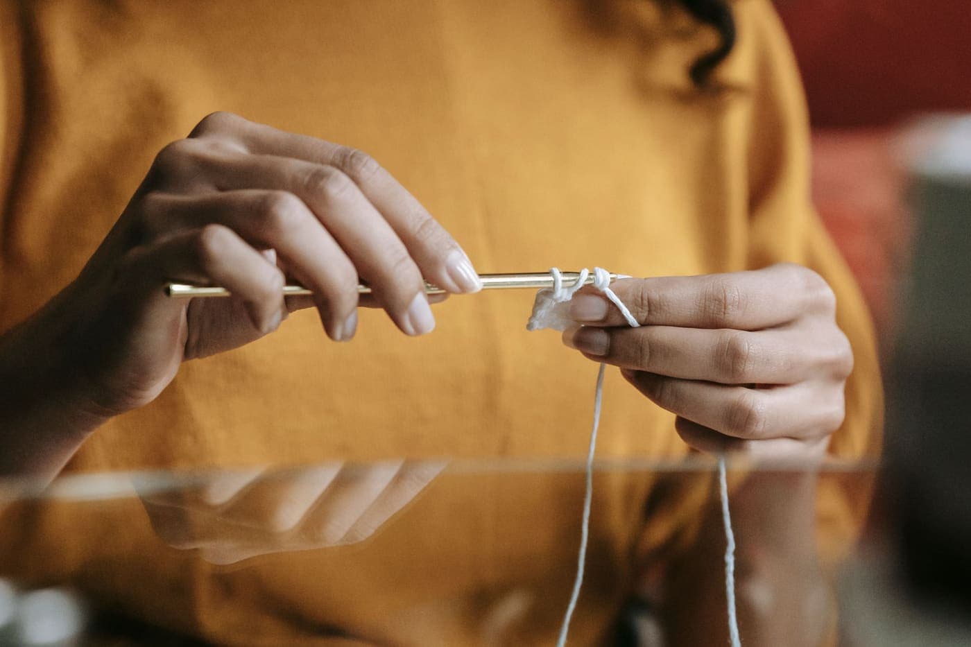 Close-up of hands working a crochet hook through fine yarn