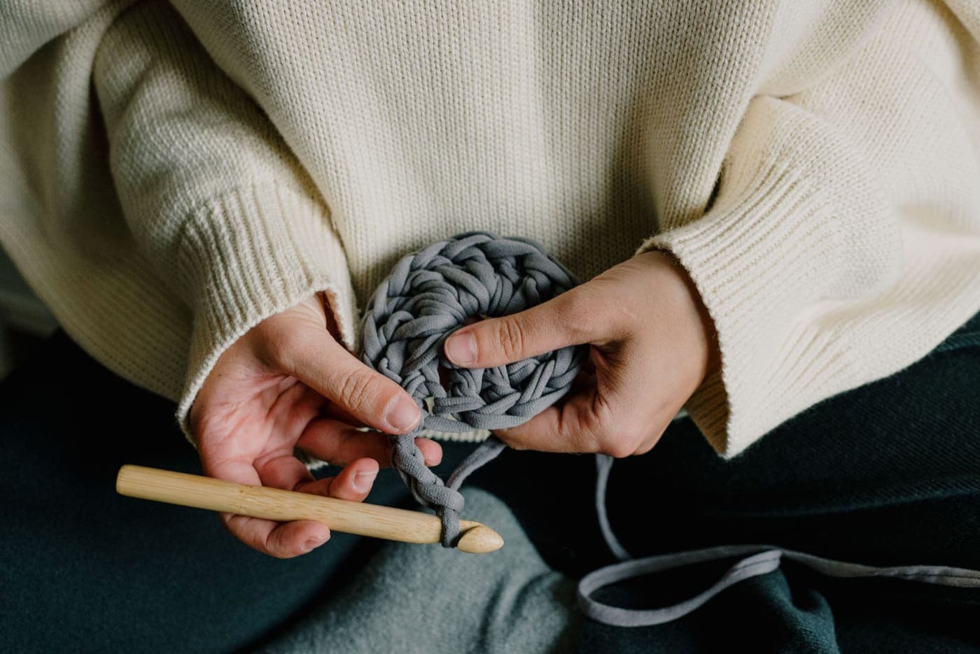 Hands using a crochet hook with gray yarn