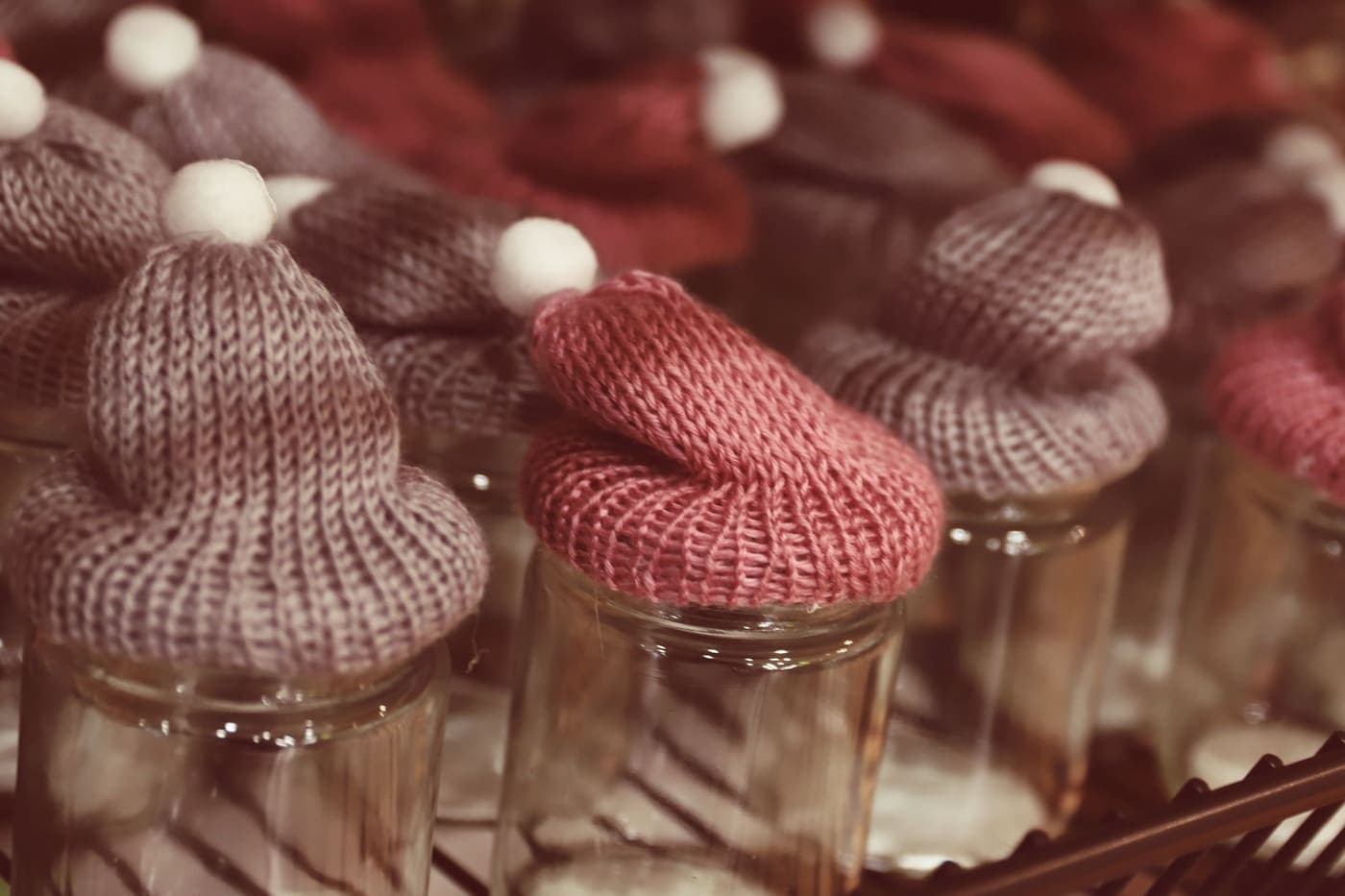 Knitted beanies displayed on jars at a market stand