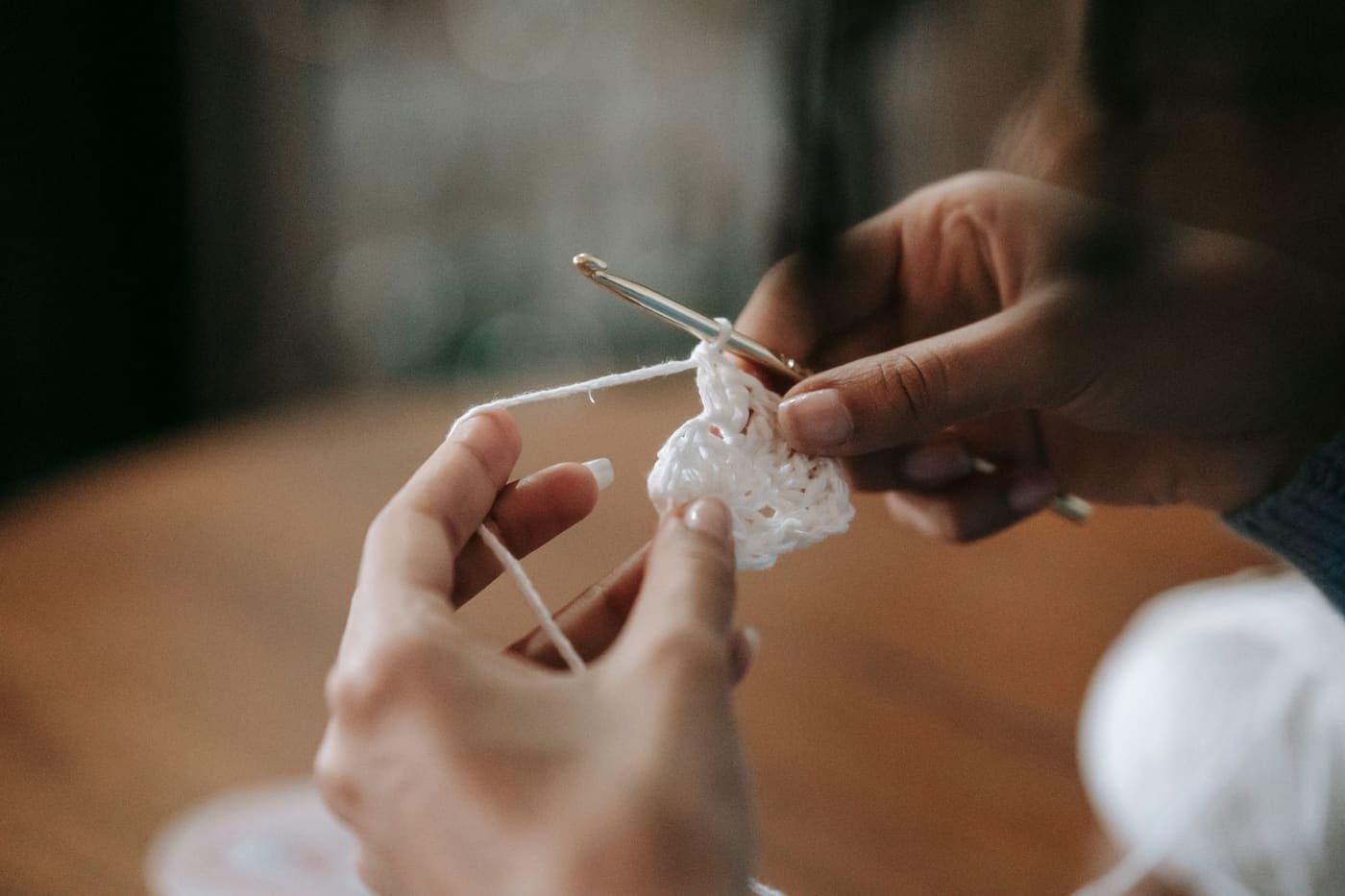 Close-up of hands working a crochet hook with white yarn