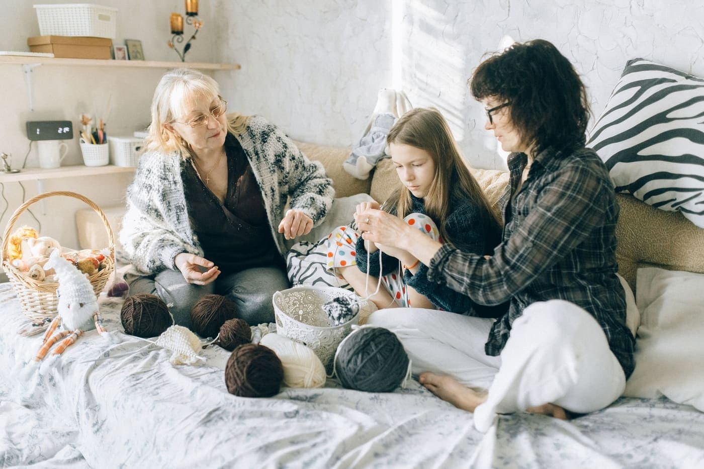 Three generations crocheting together on a bed