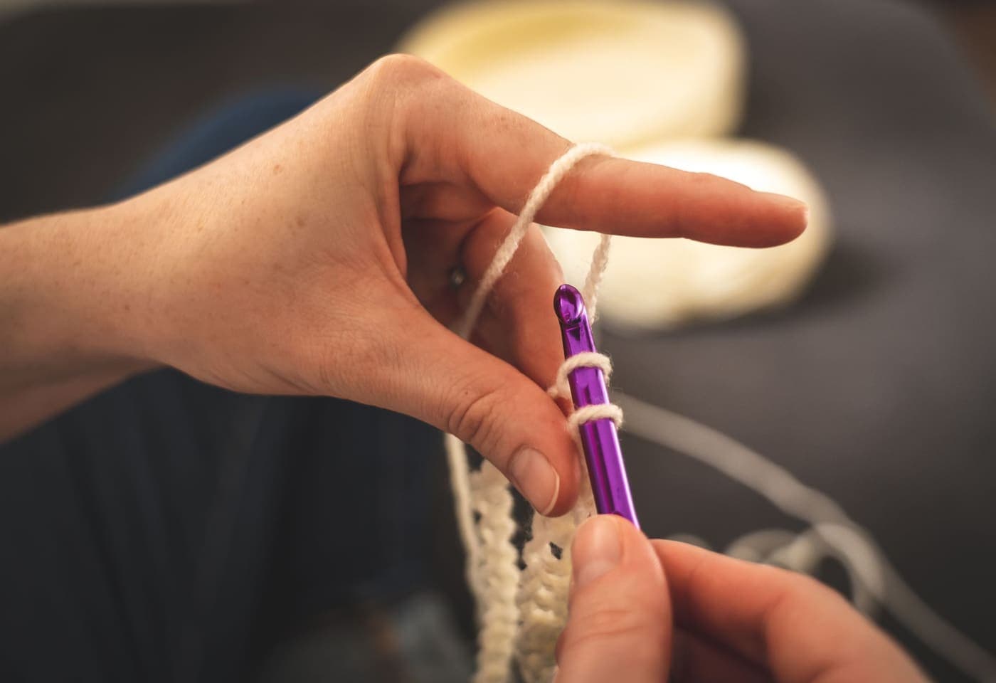 Close-up of hands crocheting with a purple hook