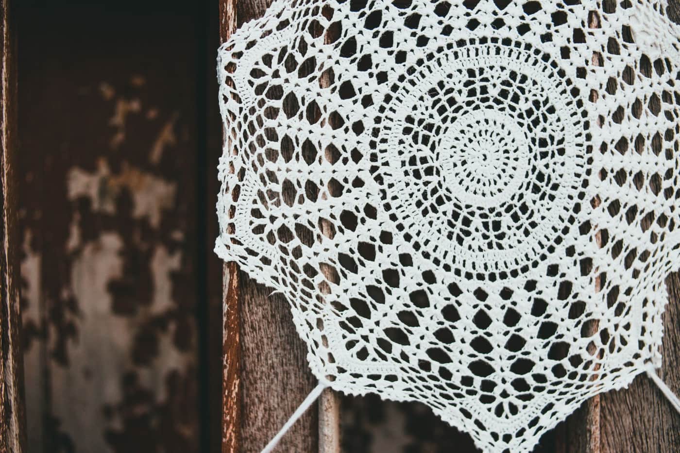 A handmade crochet doily with an intricate openwork pattern on a rustic wooden background