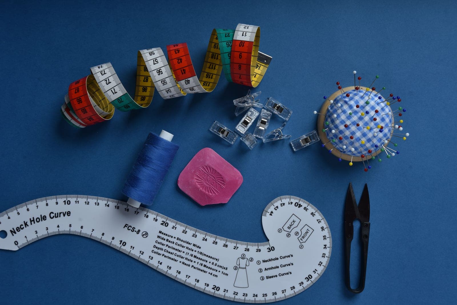 A yarn ball winder, stitch markers and a project bag on a work table