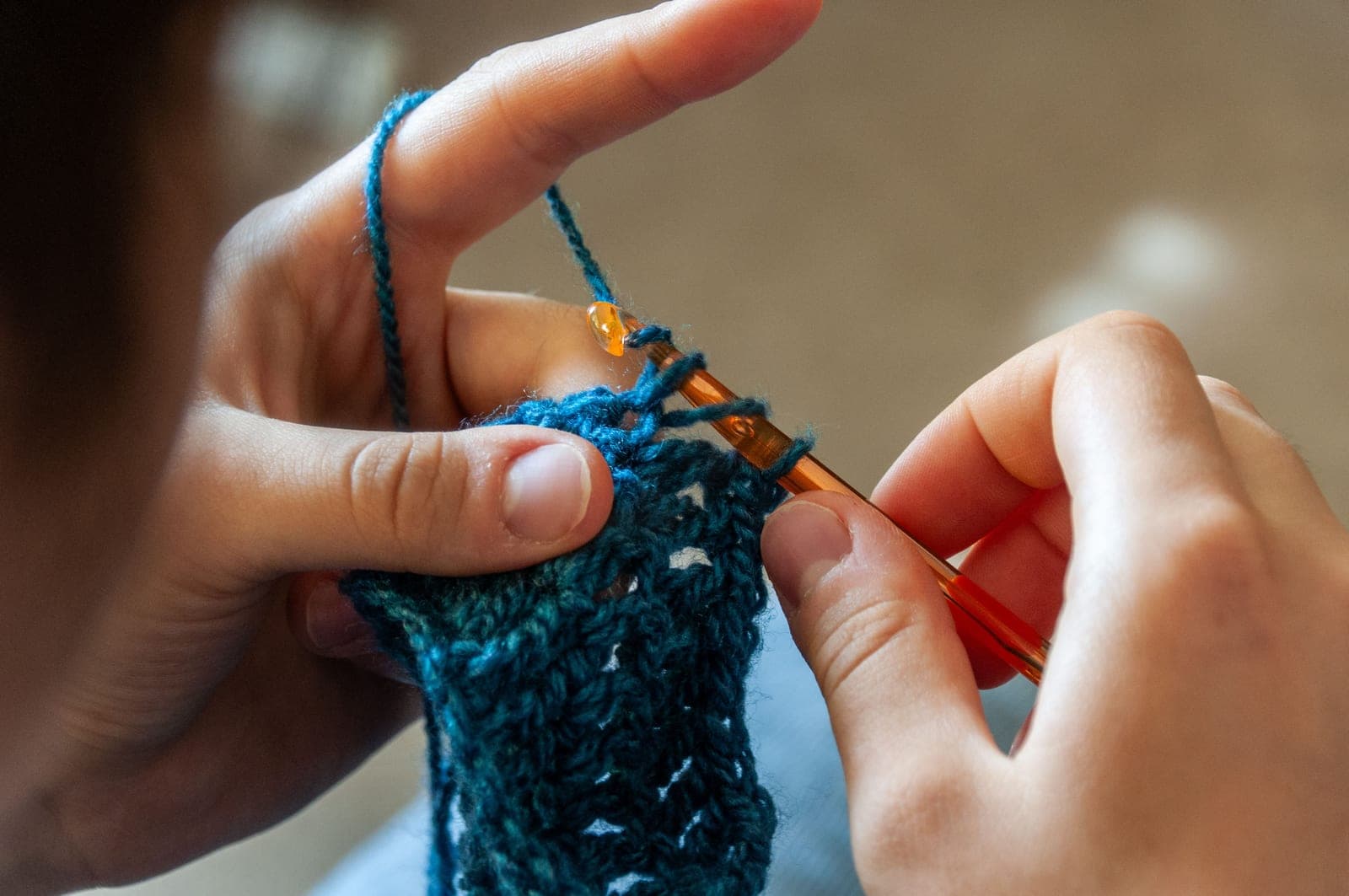 Hands working a row of crochet stitches in natural light