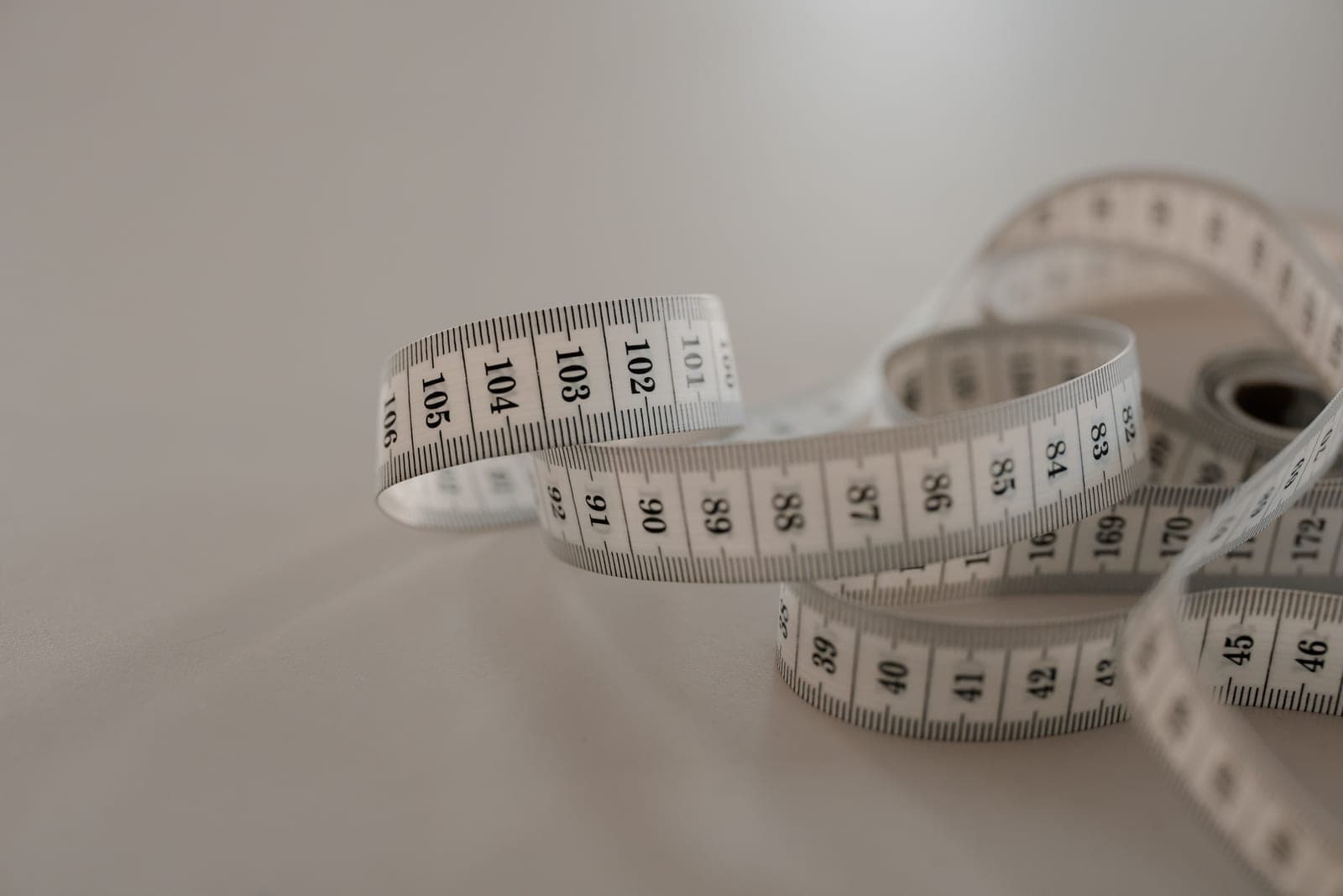 A knitting gauge ruler laid across a swatch with a tape measure alongside