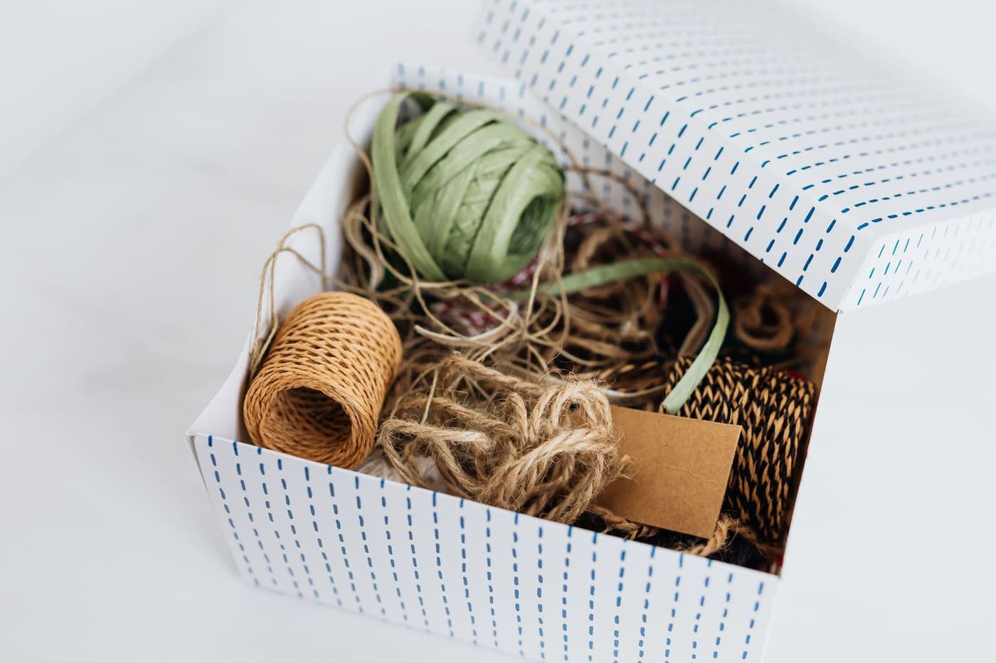 An open box of ribbons and cords for wrapping presents on a white table