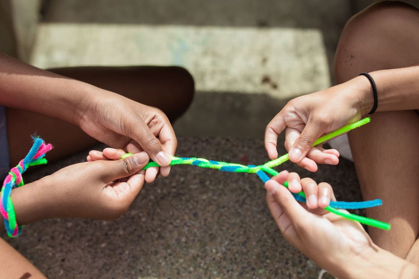 Close-up of children making colorful yarn bracelets at a craft table