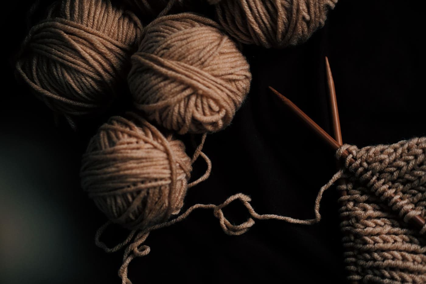 A flat lay of brown yarn balls and knitting needles