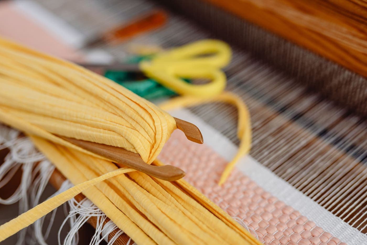 A close-up of yellow threads stretched across a loom