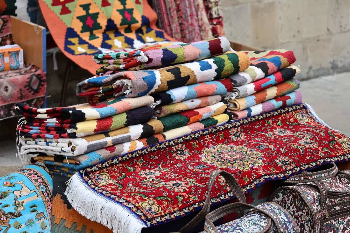 Colorful traditional woven rugs displayed at an outdoor market