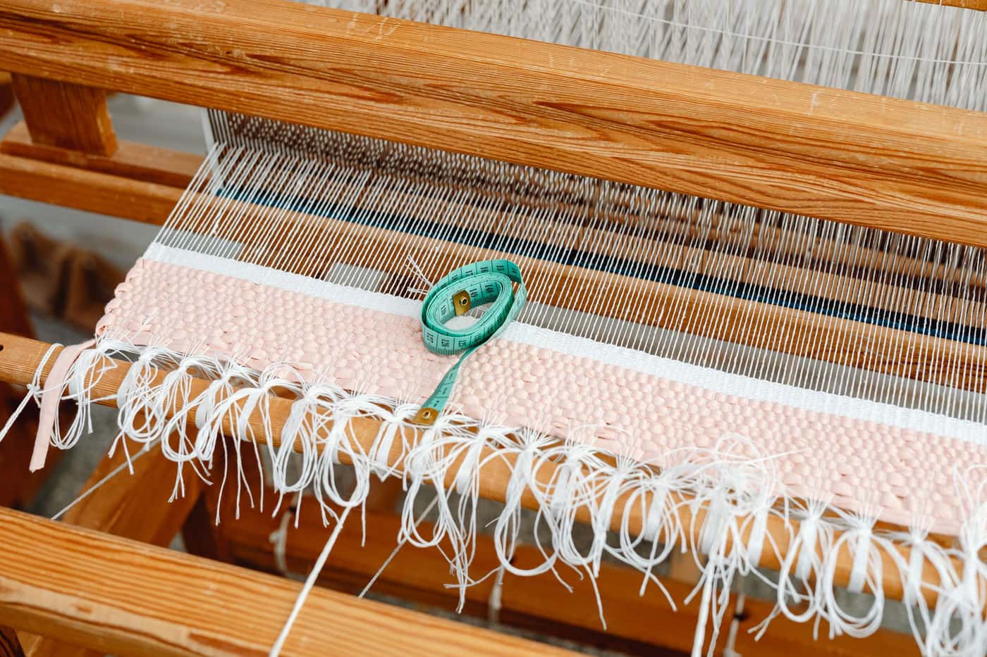 A measuring tape resting on the threads of a loom