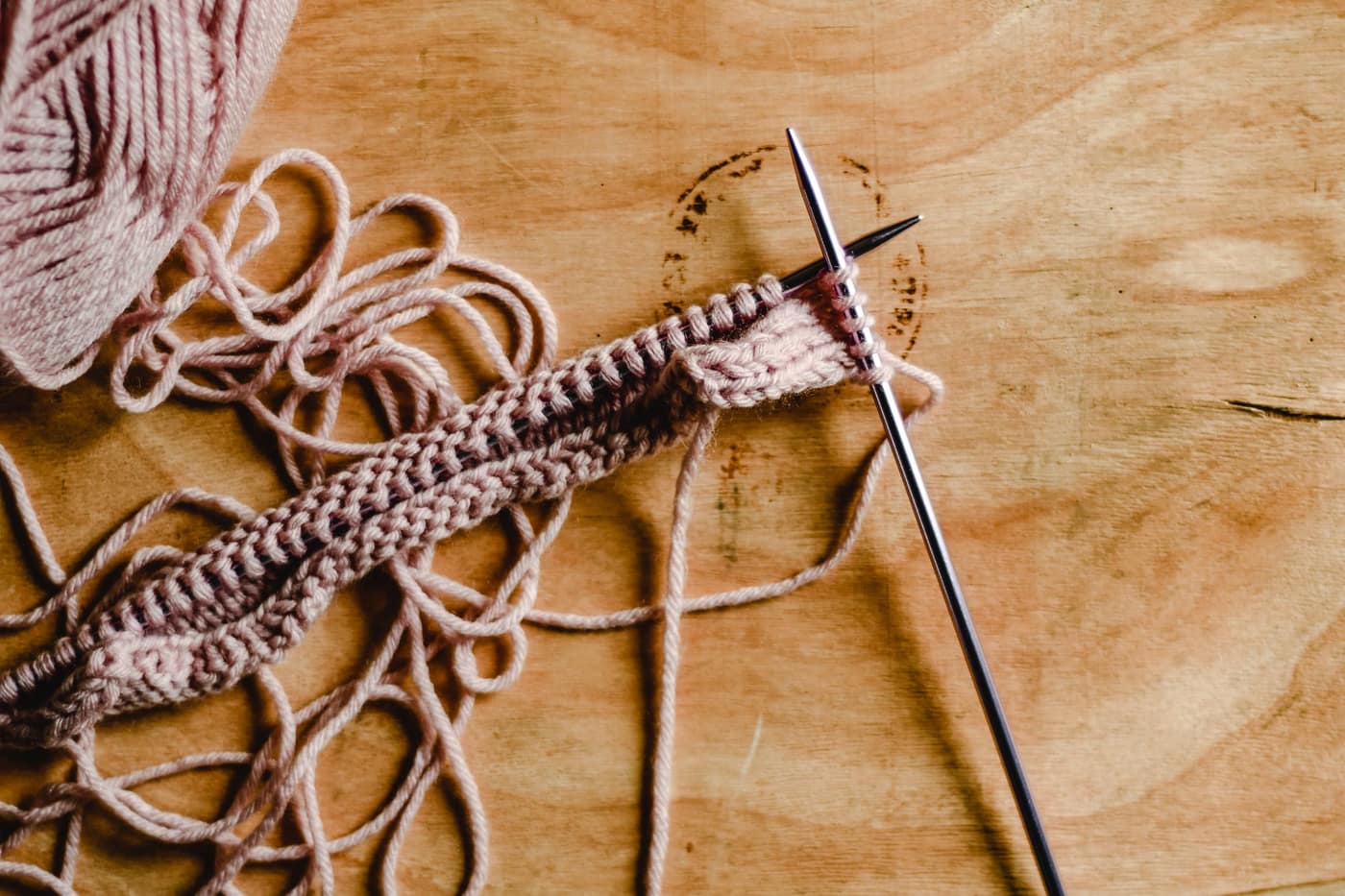 Yarn and knitting needles arranged on a wooden table
