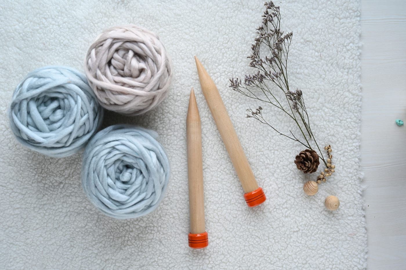 A bamboo knitting needle laid beside a stainless steel one