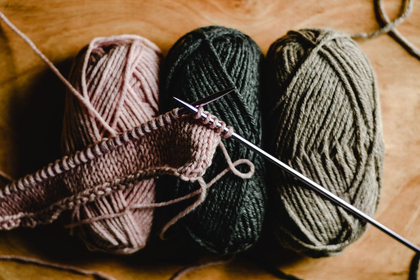 A pair of bamboo knitting needles with a beginner swatch of worsted yarn