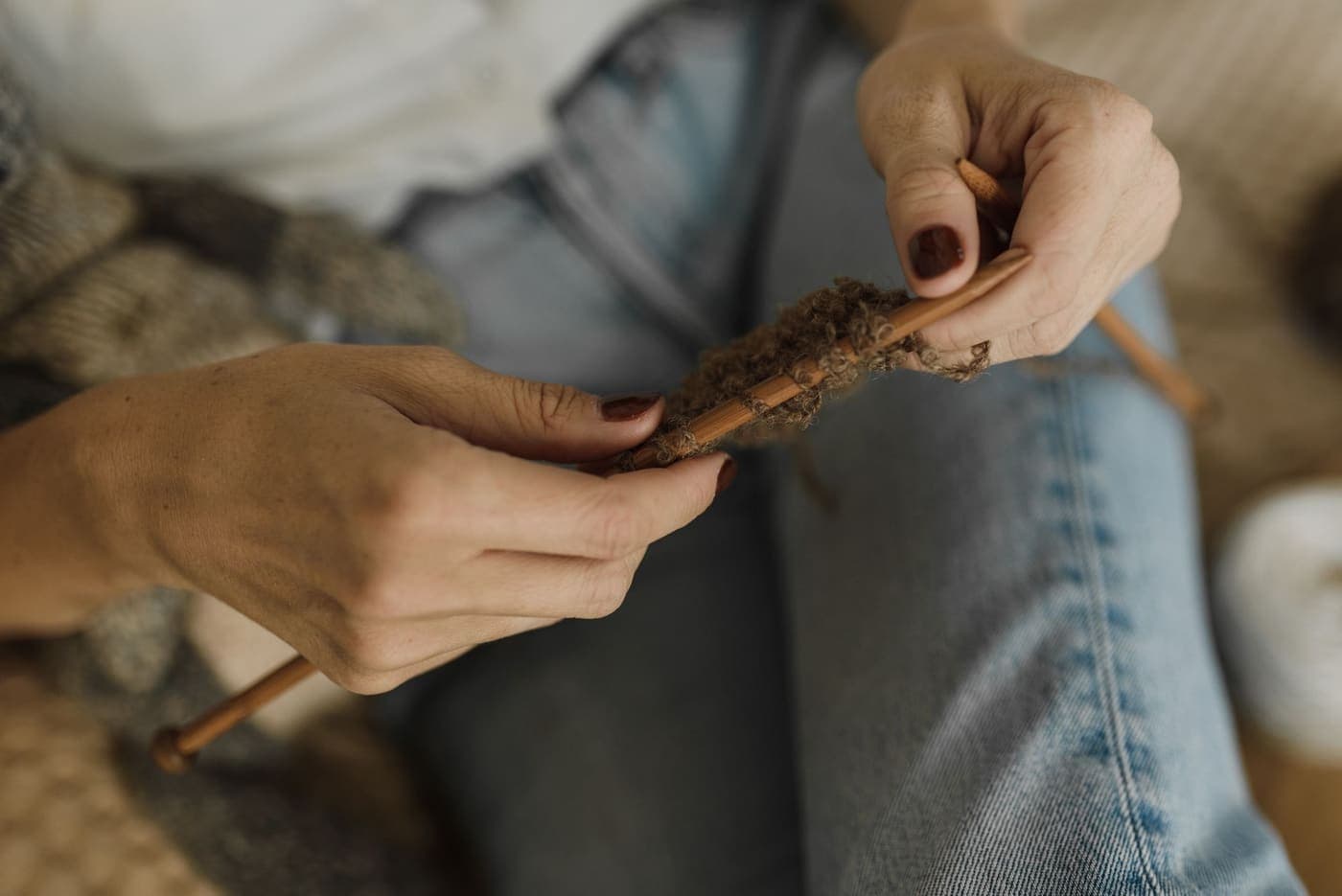 Close-up of a person knitting with brown yarn in a cozy setting