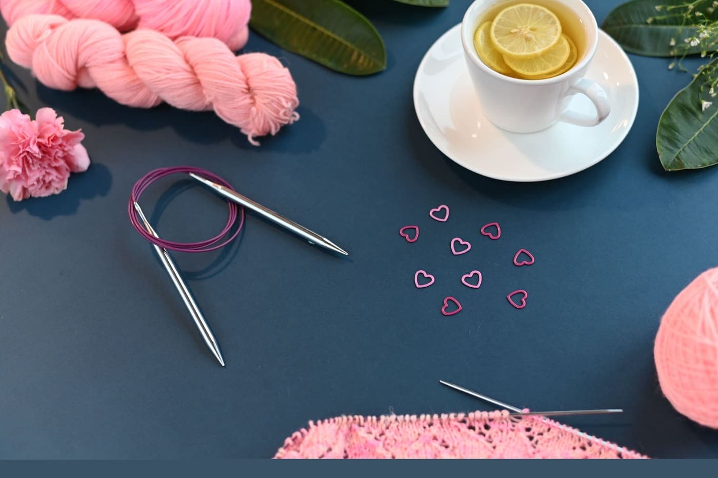 A flat lay of knitting supplies with a cup of lemon tea