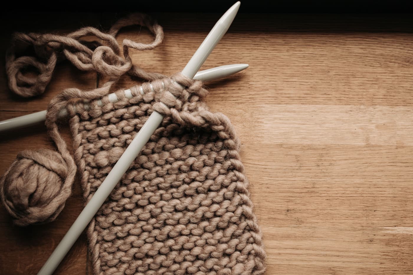 Large knitting needles working a swatch of super bulky yarn