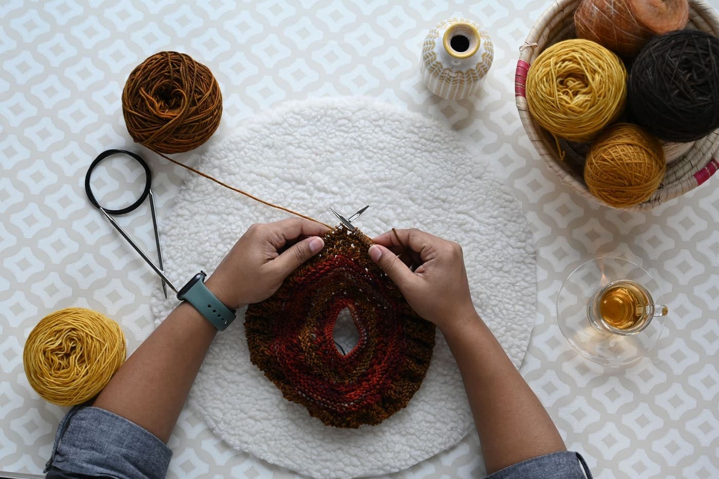 Hands knitting with brightly colored yarn seen from above
