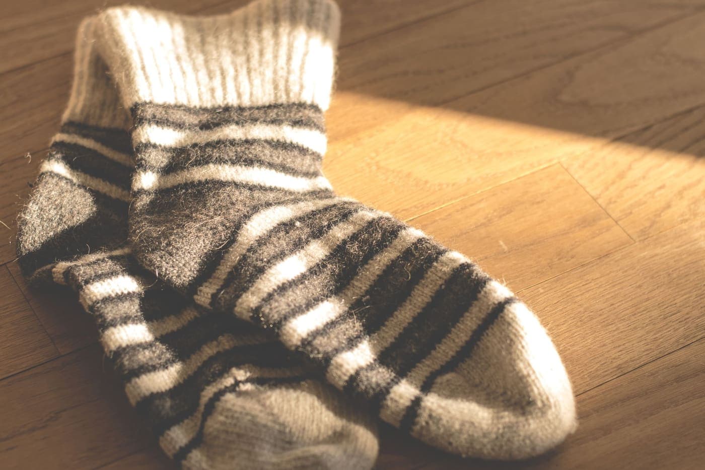 A pair of warm knitted striped socks on a wooden floor