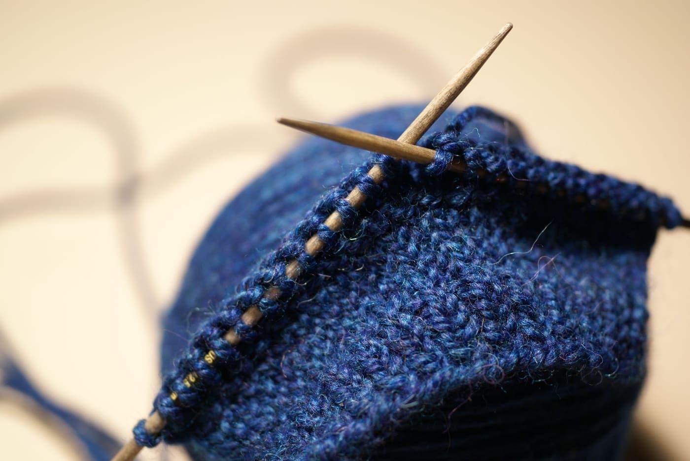 Fine blue knitting in progress on slim wooden needles