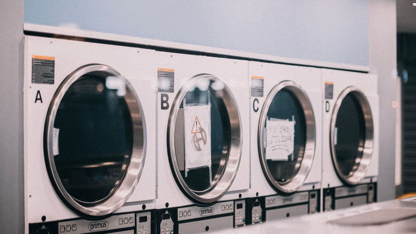A row of industrial washing machines labeled A to D in a modern laundromat