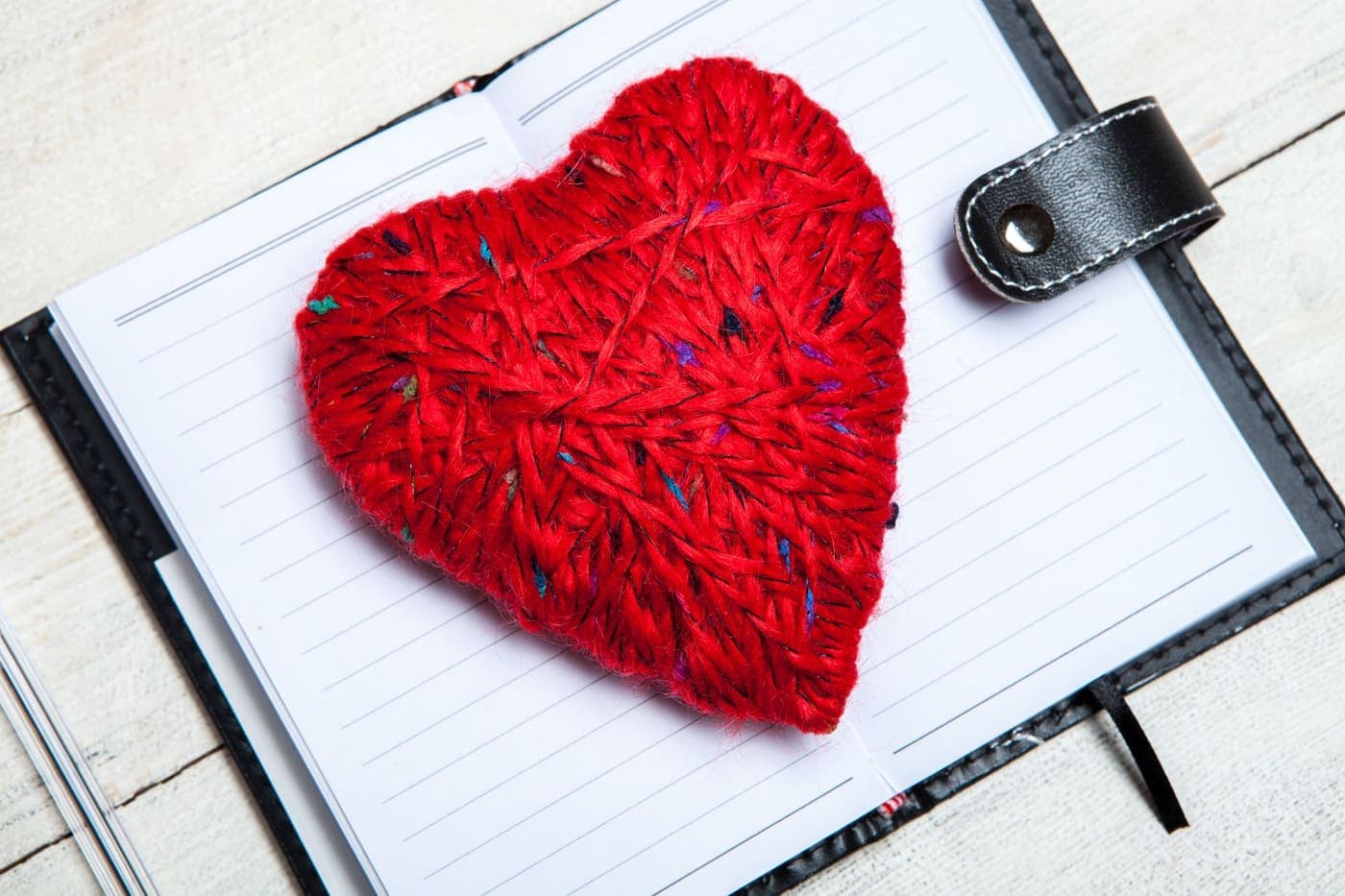 A red yarn heart resting on an open notebook